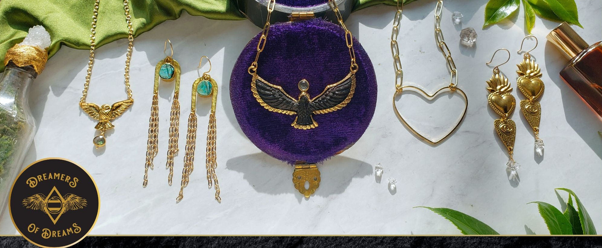 Jewelry set with necklaces, earrings, and a purple pouch on a white background.